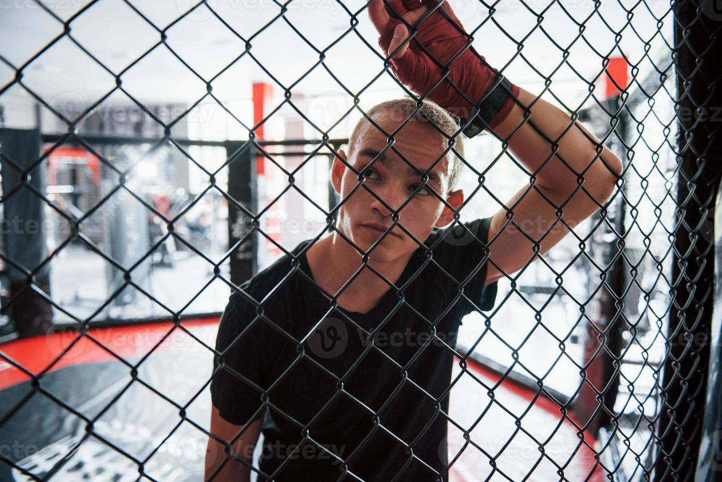 Taking a break. Sportsman at boxing ring have exercise. Leaning on the fence photo