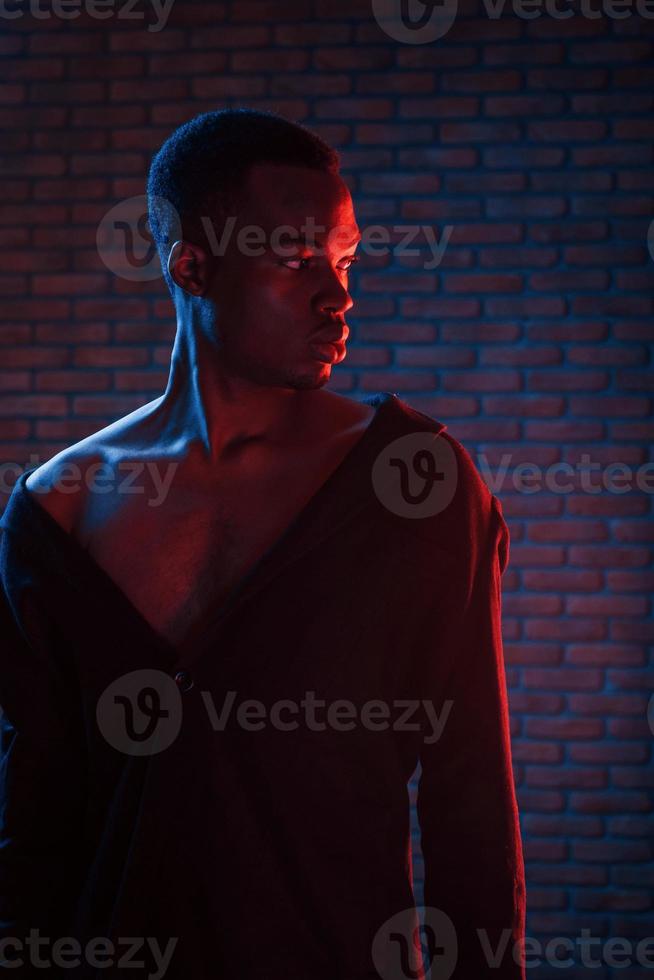 Vertical photo. Futuristic neon lighting. Young african american man in the studio photo