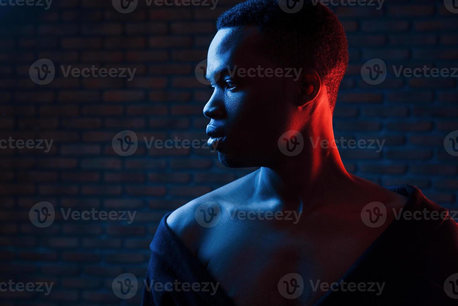 Confident guy. Futuristic neon lighting. Young african american man in the studio photo