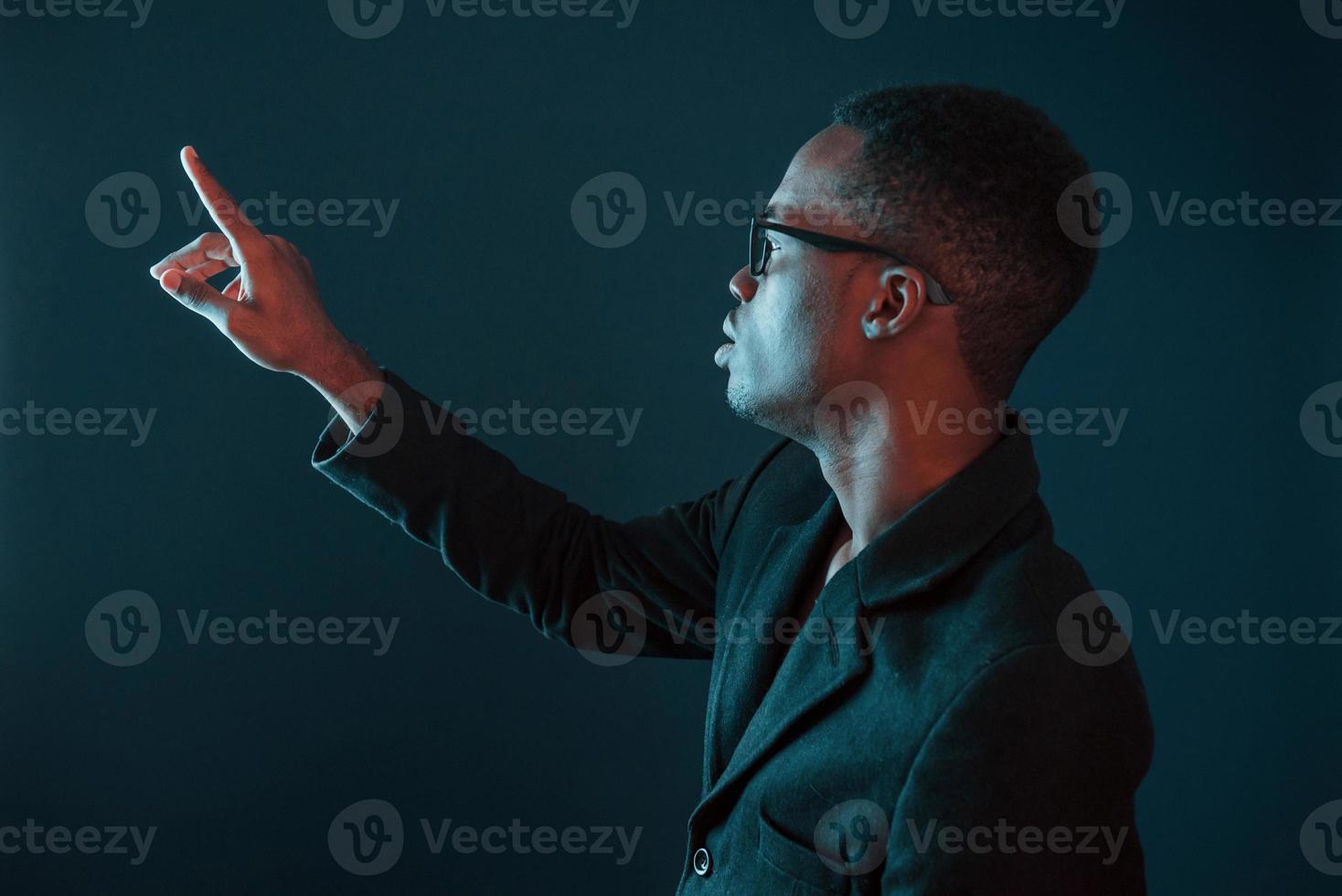 Hands in front. Futuristic neon lighting. Young african american man in the studio photo