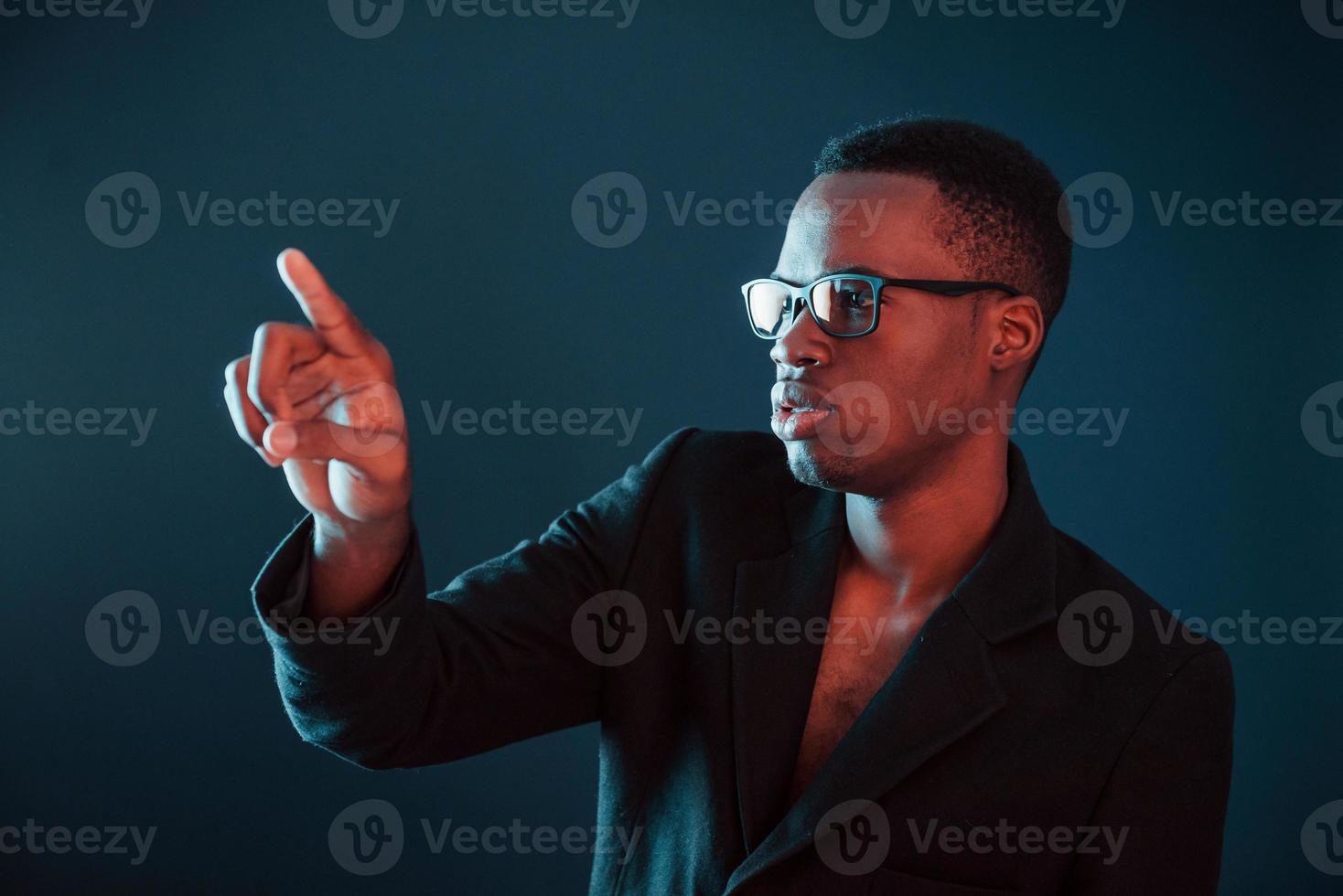 Hands in front. Futuristic neon lighting. Young african american man in the studio photo