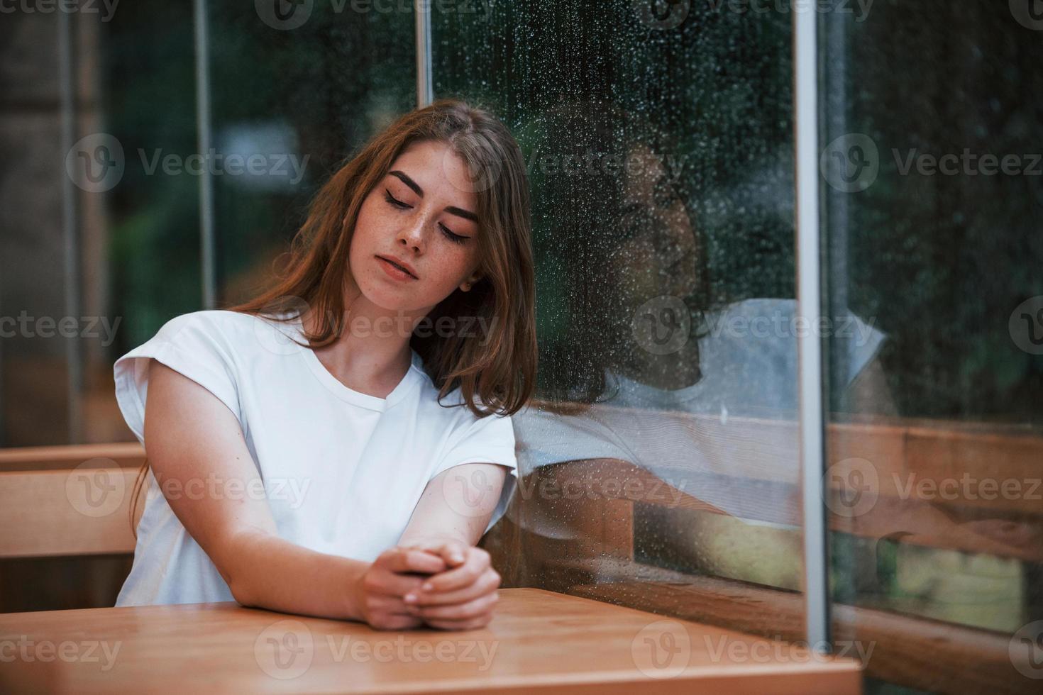 Portrait of young girl that sits in cafe at rainy day. One person only photo