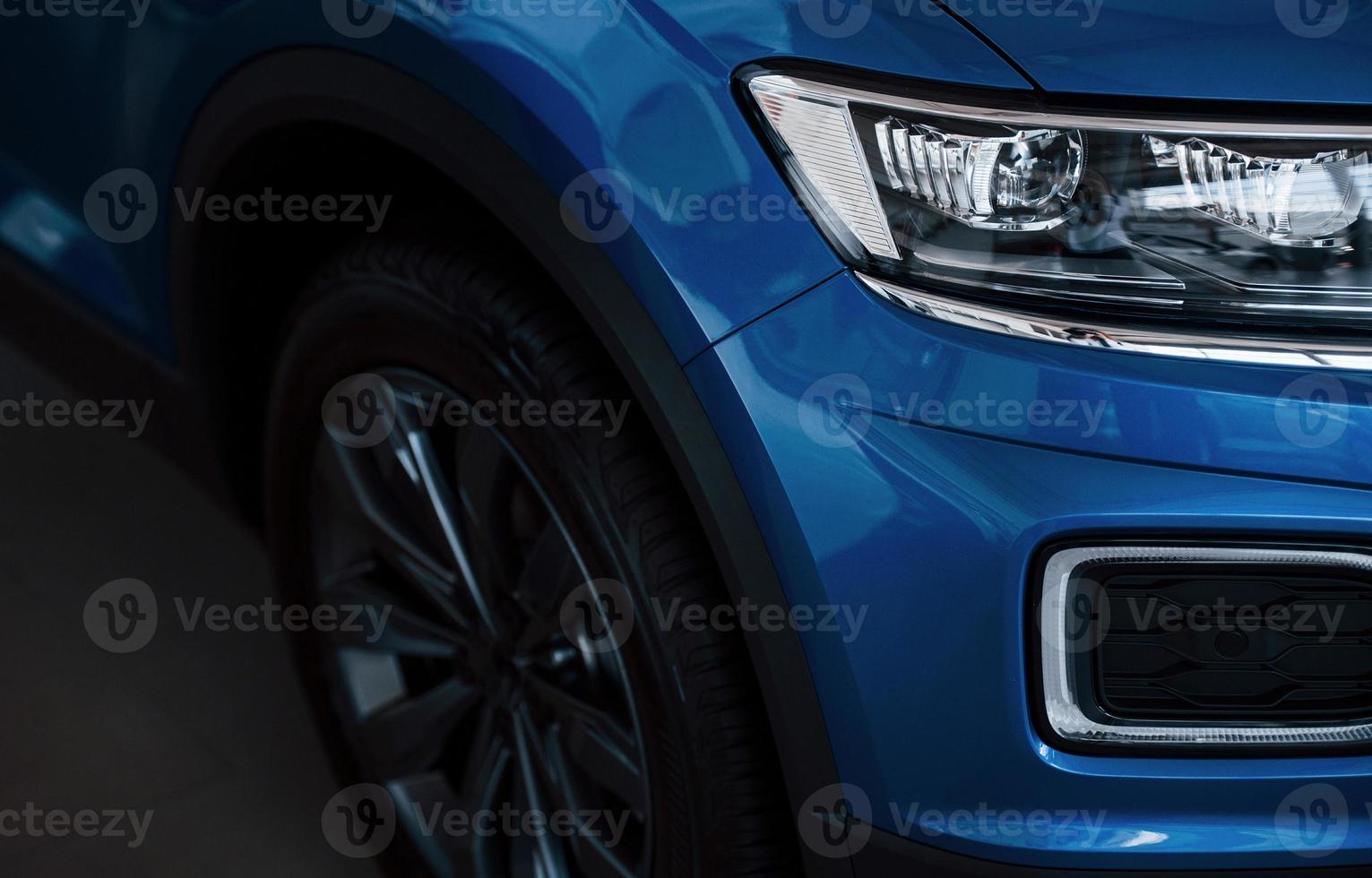 Front part of brand new modern blue car. Parked at showroom. Reflection in the headlights photo