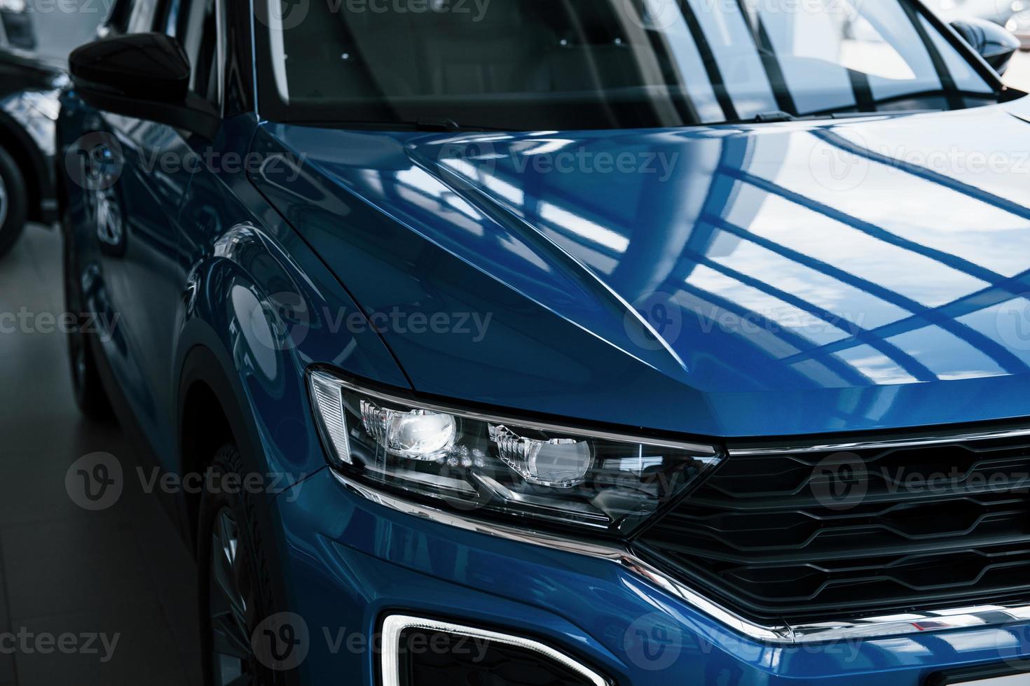 Front part of brand new modern blue car. Parked at showroom. Reflection in the headlights photo