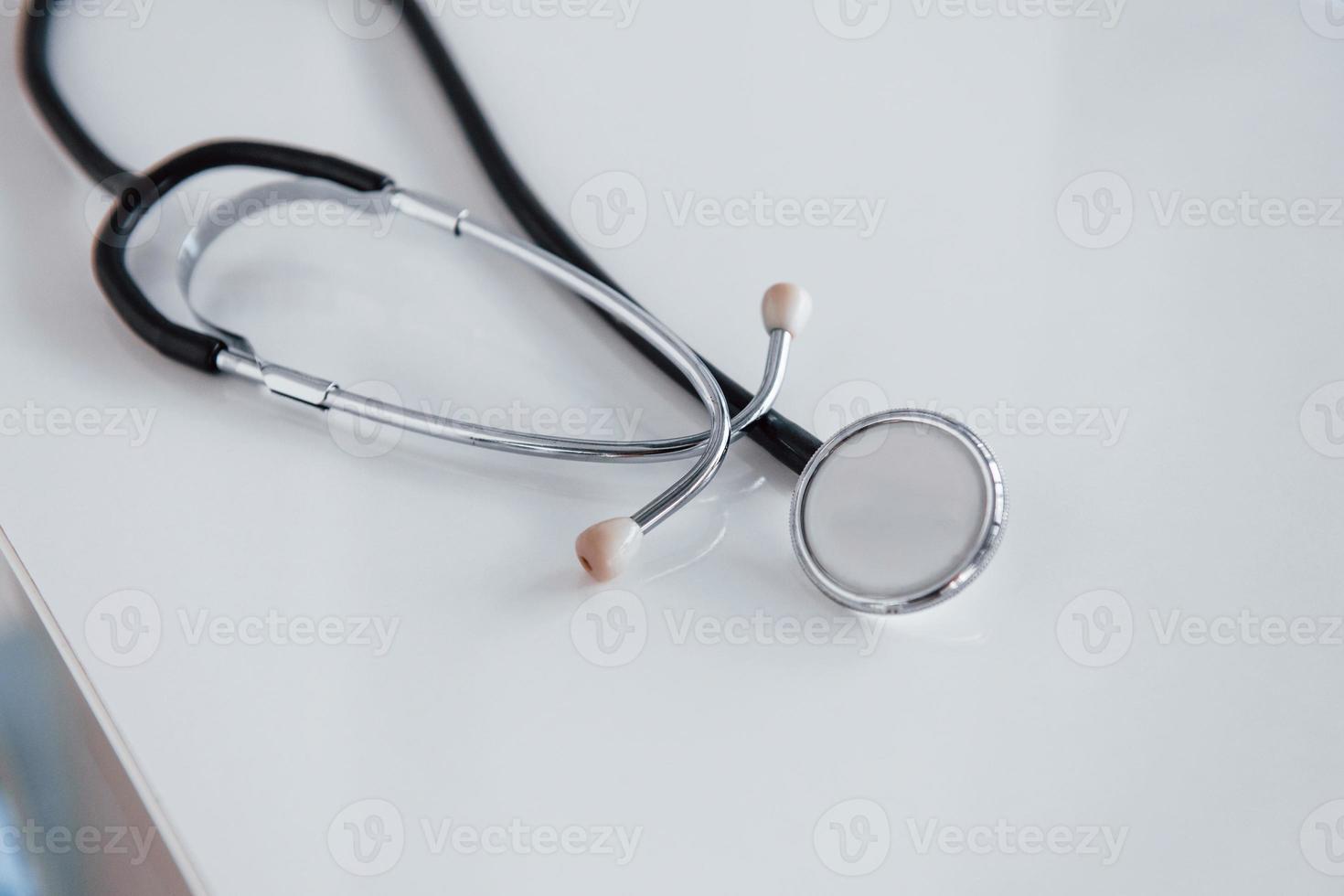 Close up view of medical stethoscope that lying down on white table photo