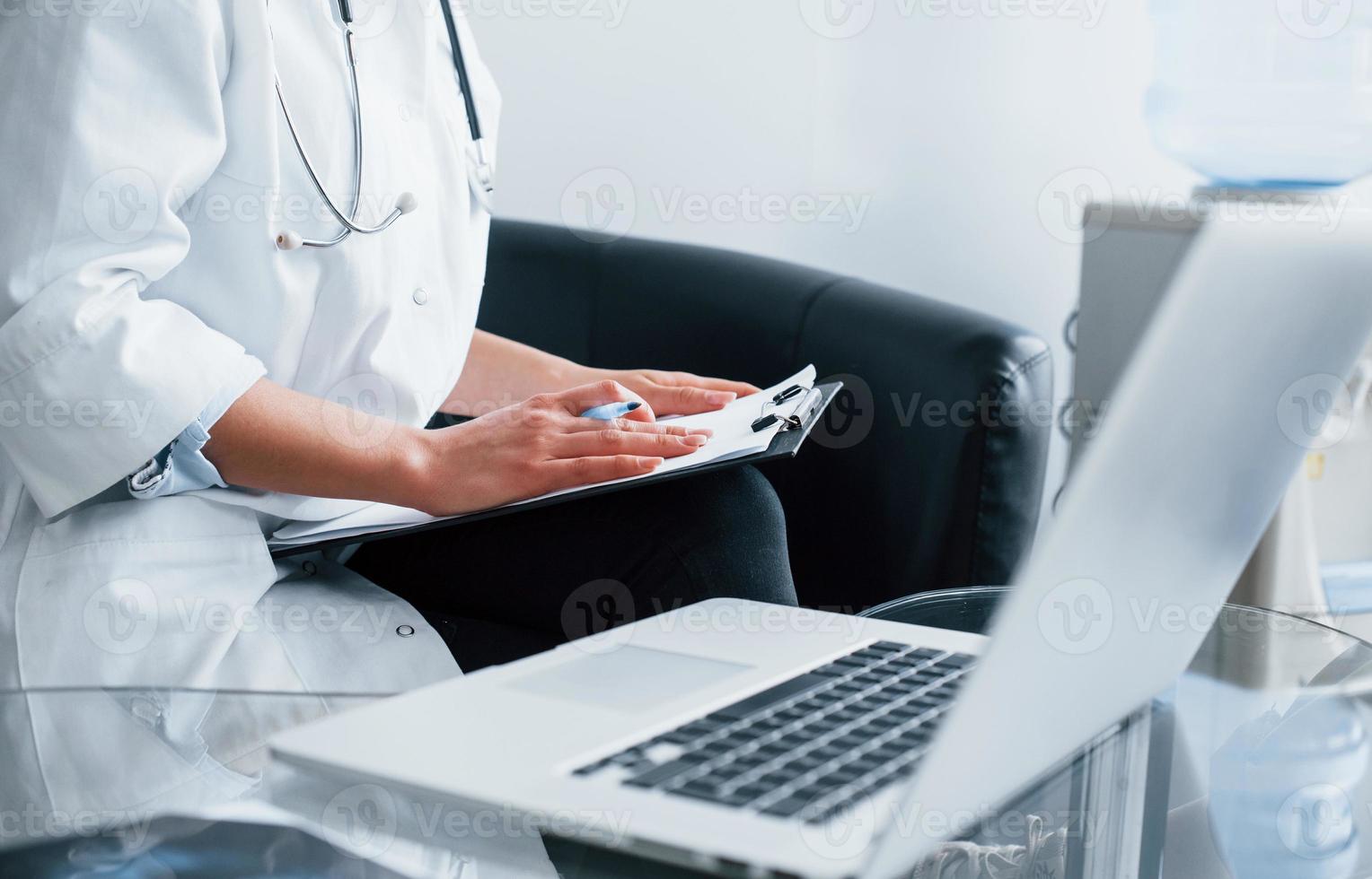 With notepad. Young nurse indoors in modern clinic. Conception of healthcare photo