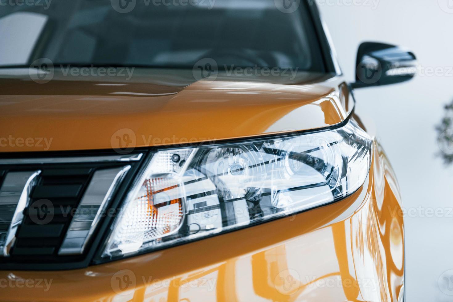 Close up particle view of brand new car's front part. Parked indoors photo