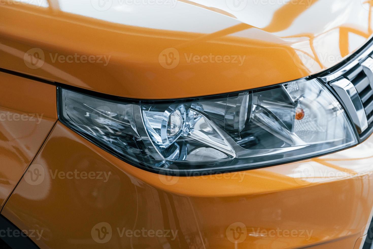 Close up particle view of brand new car's front part. Parked indoors photo