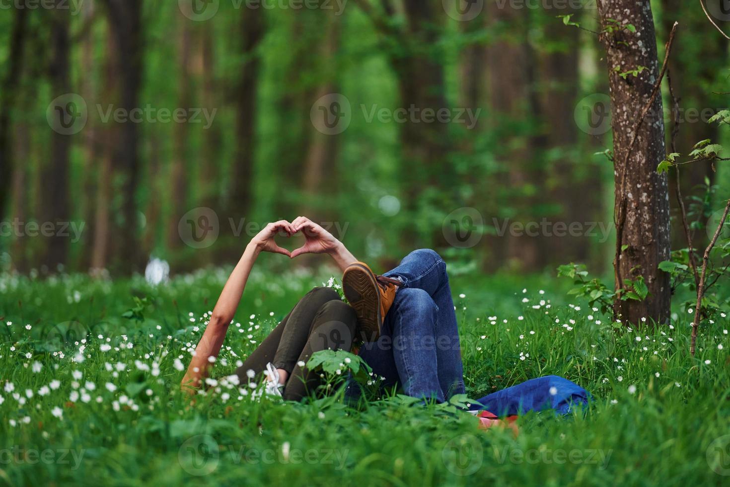 Couple lying down on the grass in forest together at daytime photo