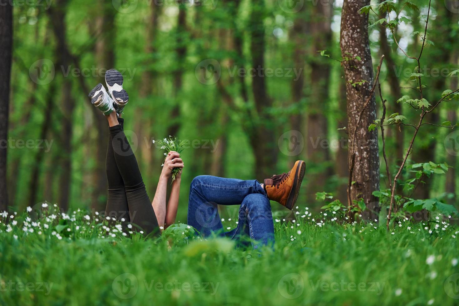 Couple lying down on the grass in forest together at daytime photo