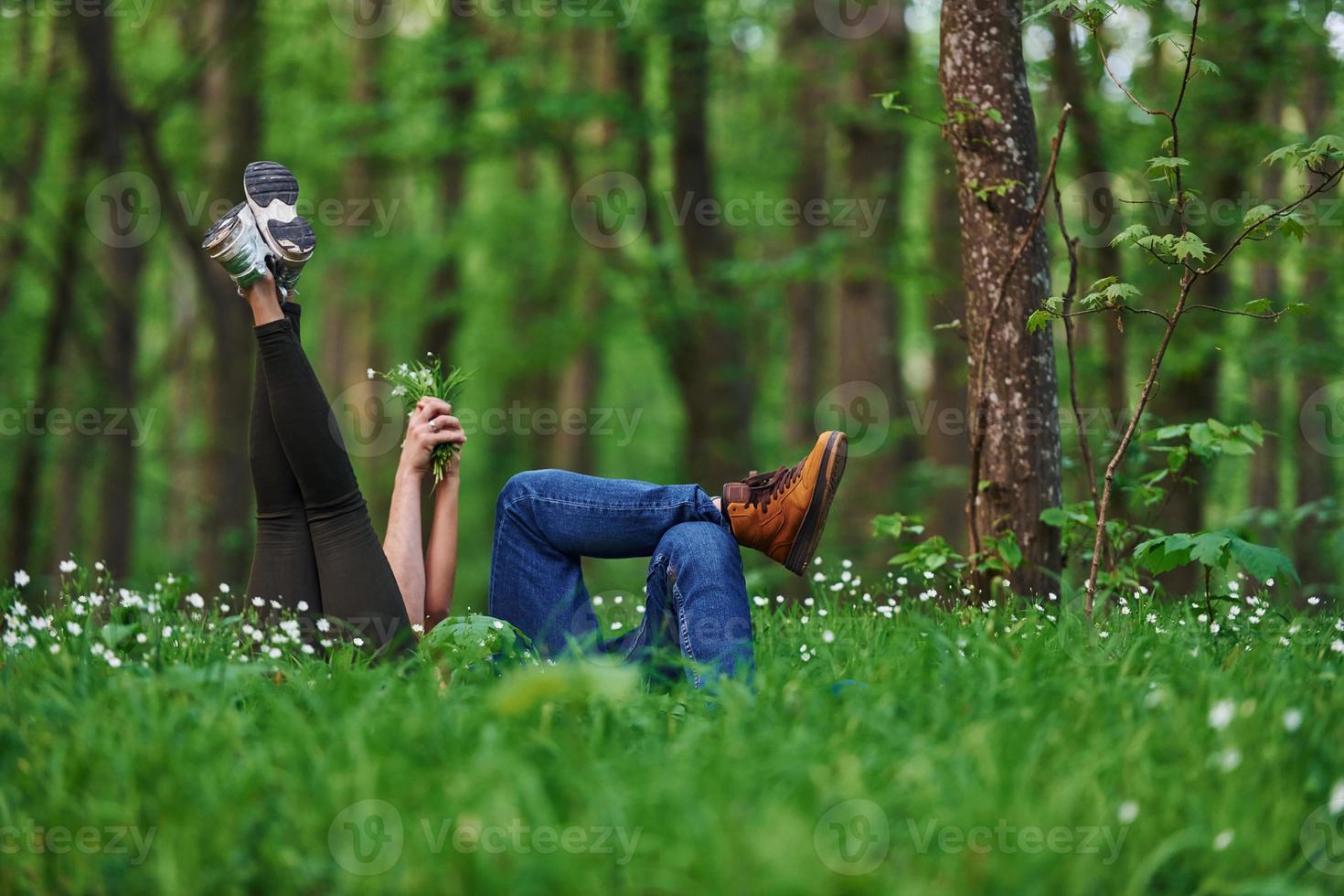 Couple lying down on the grass in forest together at daytime photo