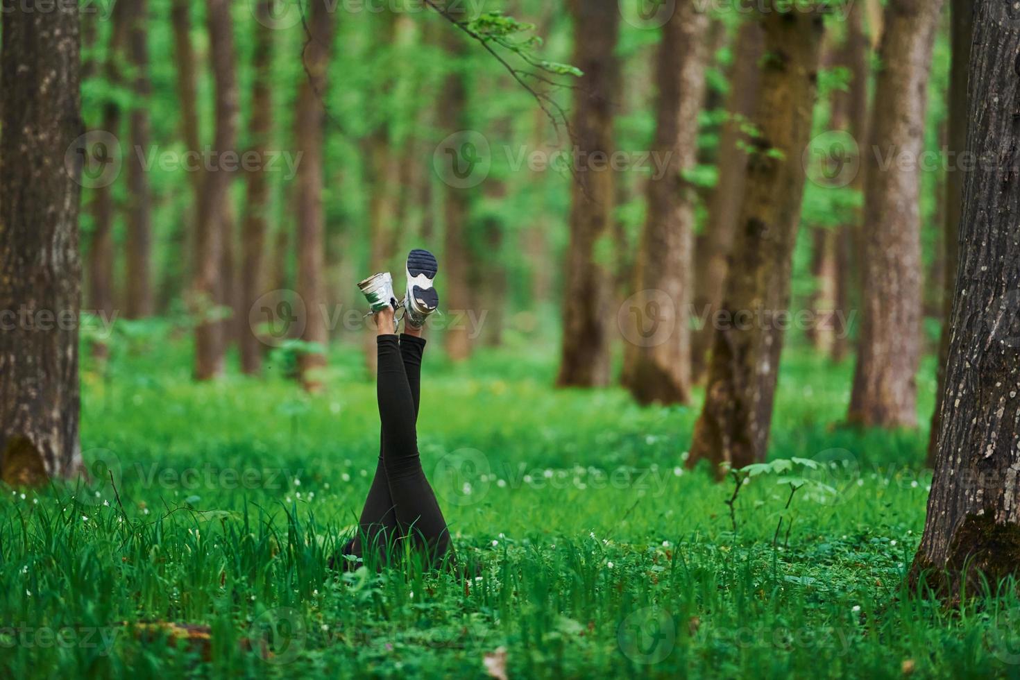 Legs of woman that have a rest and lying down on ground in forest photo