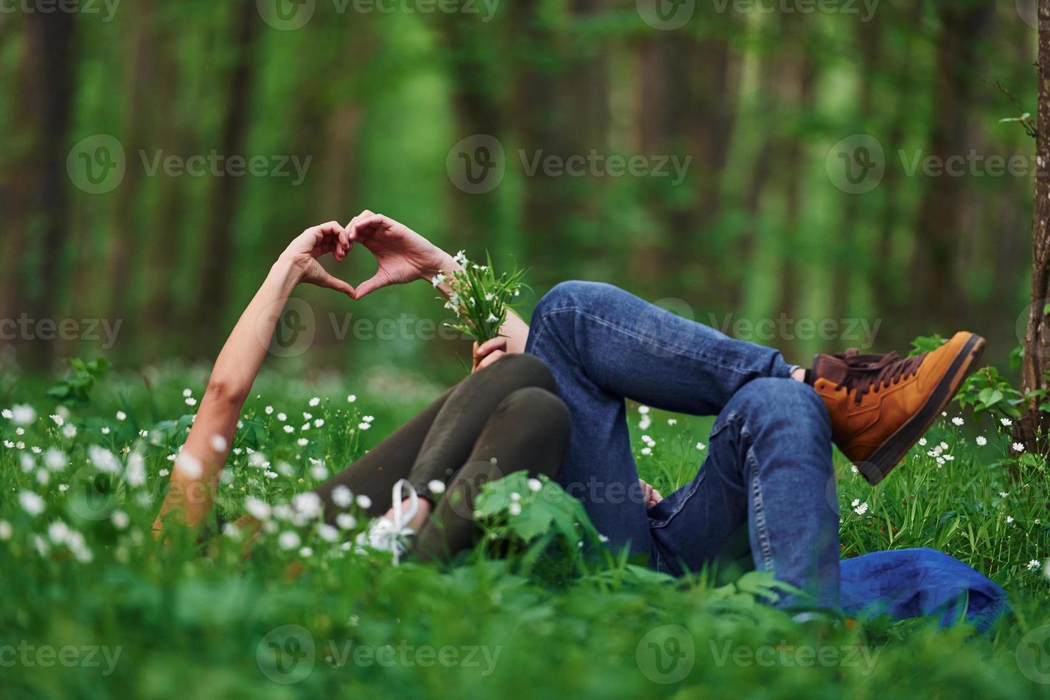 Couple lying down on the grass in forest together at daytime photo