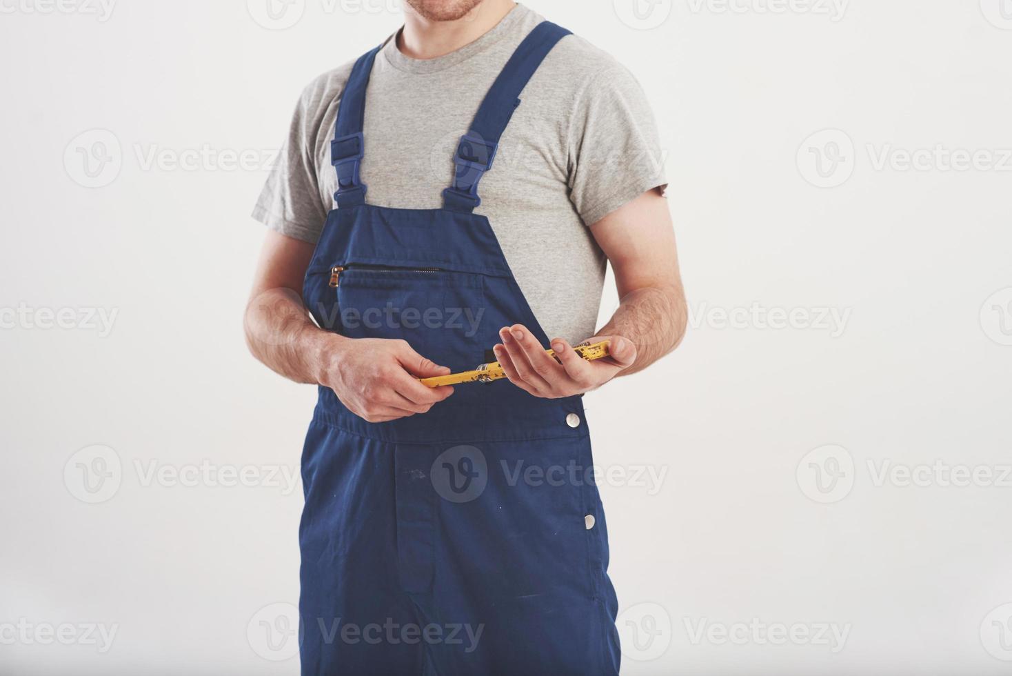 Headless view. Man in blue uniform stands against white background in the studio photo