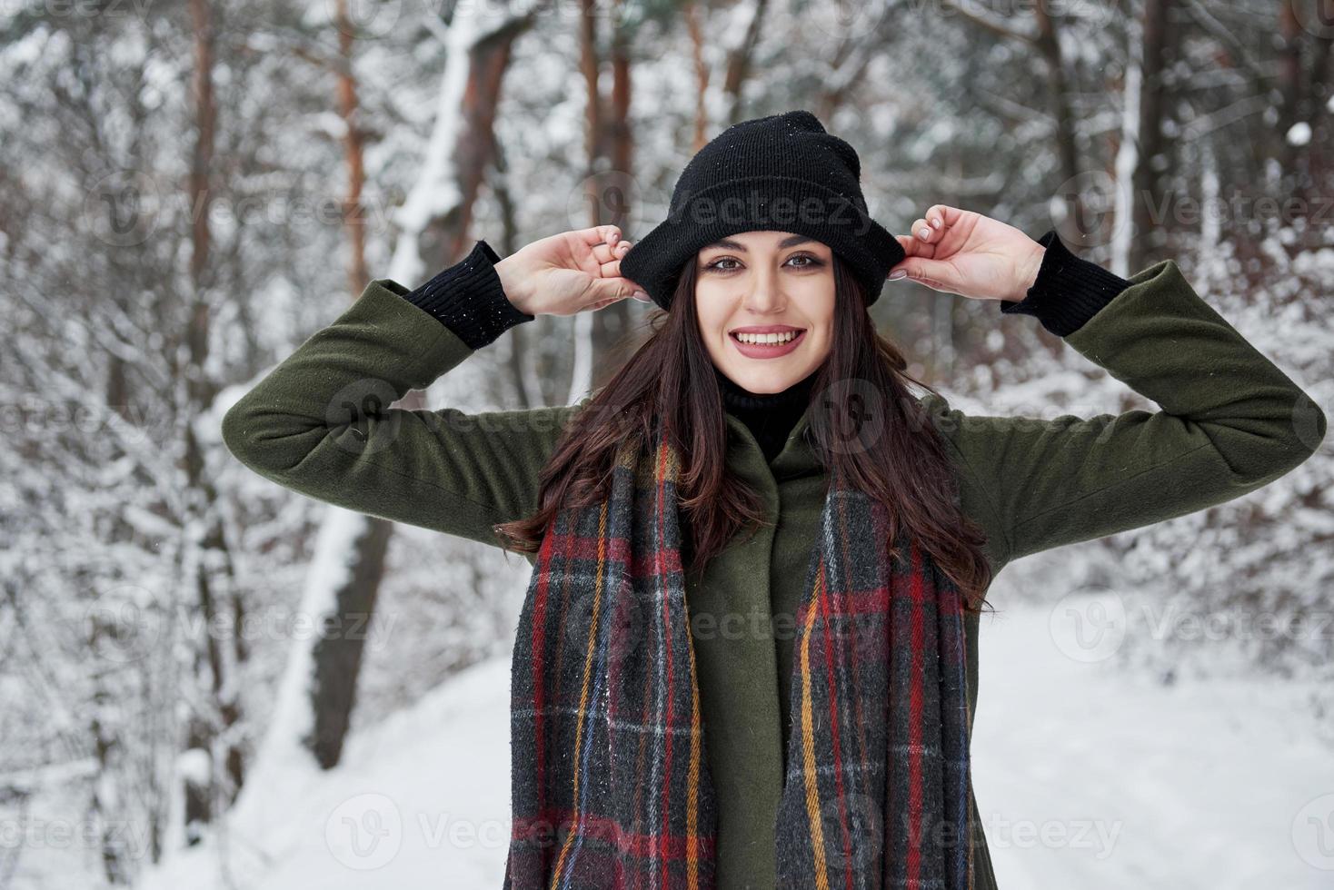 It's playful mood. Cheerful young girl in warm clothes have a walk in the winter forest at daytime photo