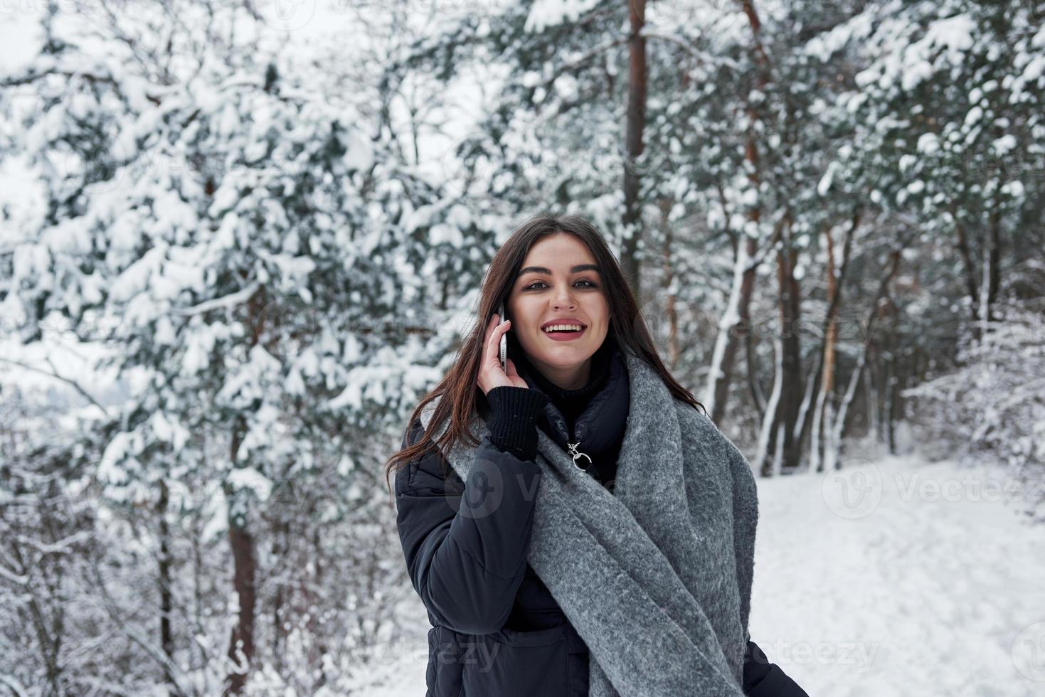 Cherful brunette have conversation while have a walk in winter forest photo