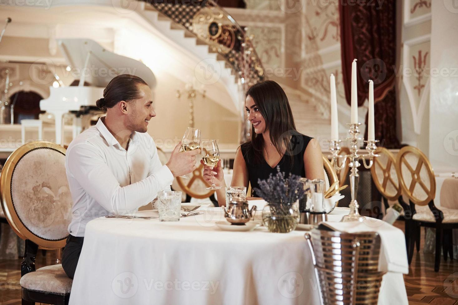 este brindis es por nosotros. una pareja hermosa tiene una cena romántica en un restaurante de lujo por la noche foto