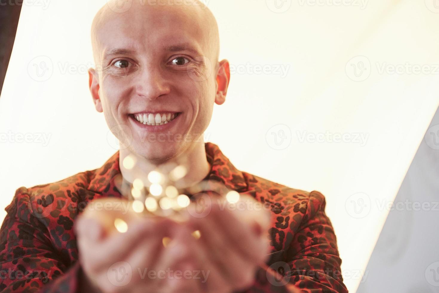 Cheerful mood. Man is smiling. Guy in the classic holiday wear holding New year garlands in front of the camera photo