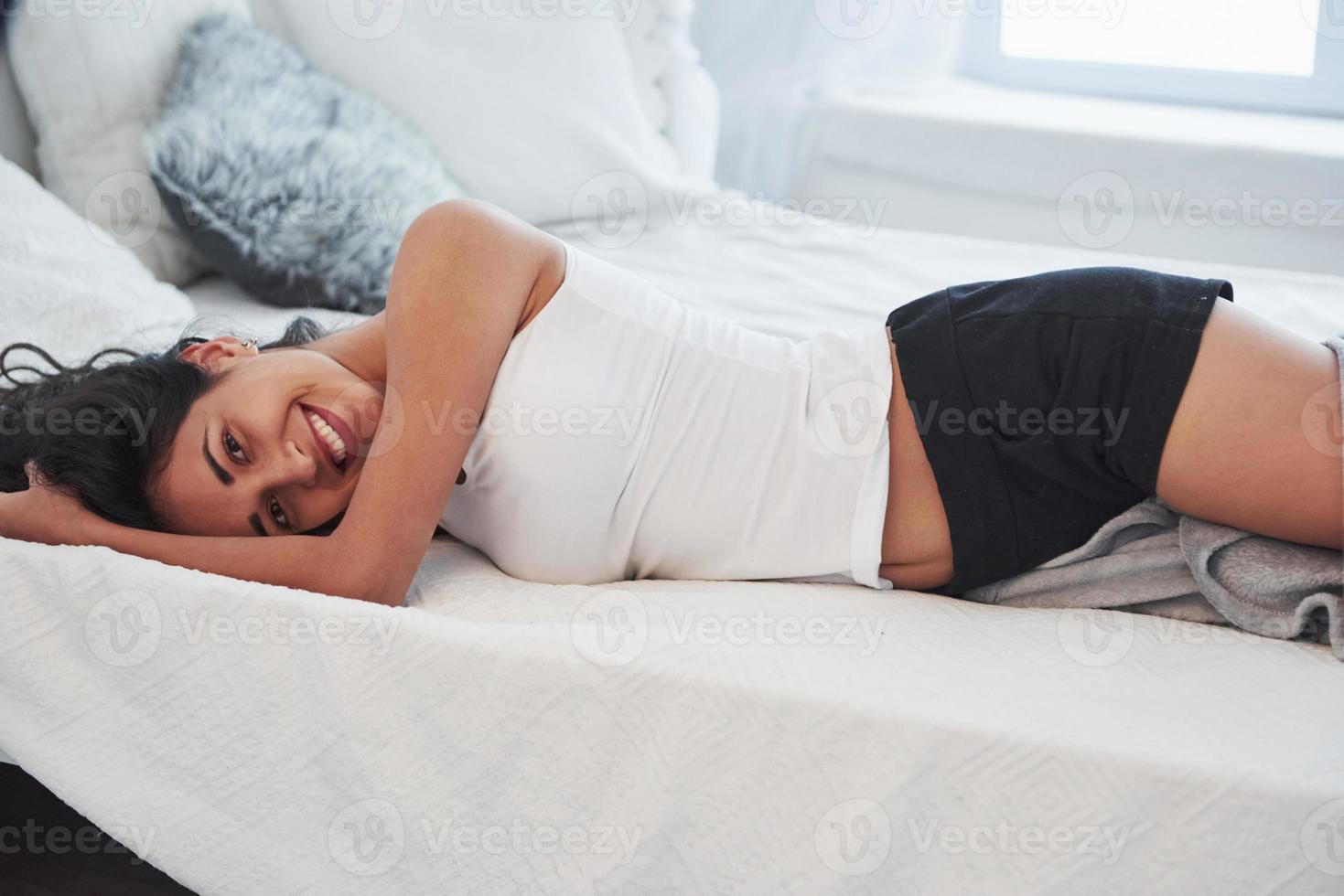 Good mood. Girl have weekend lying in the bed. Brunette resting on the couch photo