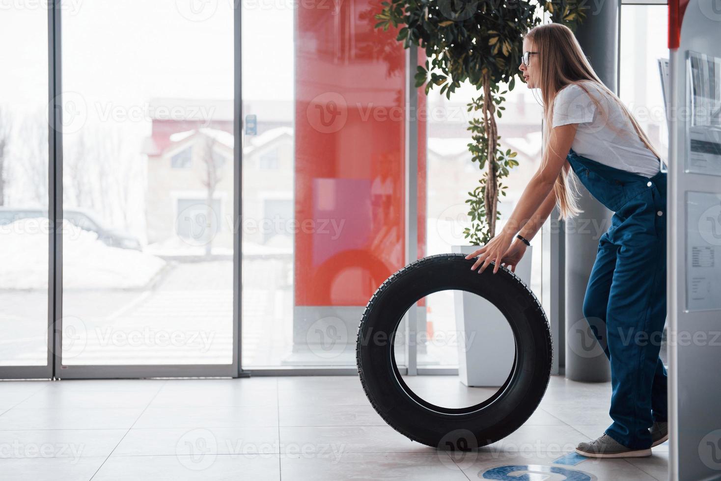 Cold weather outside. Woman walks with brand new wheel to the car. Conception of repair photo
