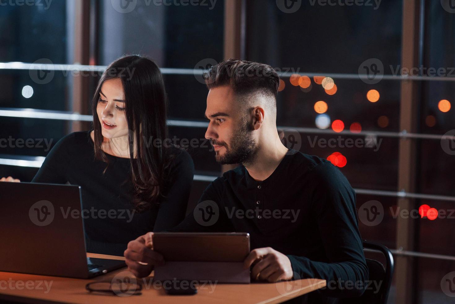 Calm and quiet atmosphere. Team of young business people works on their project at night time in the office photo