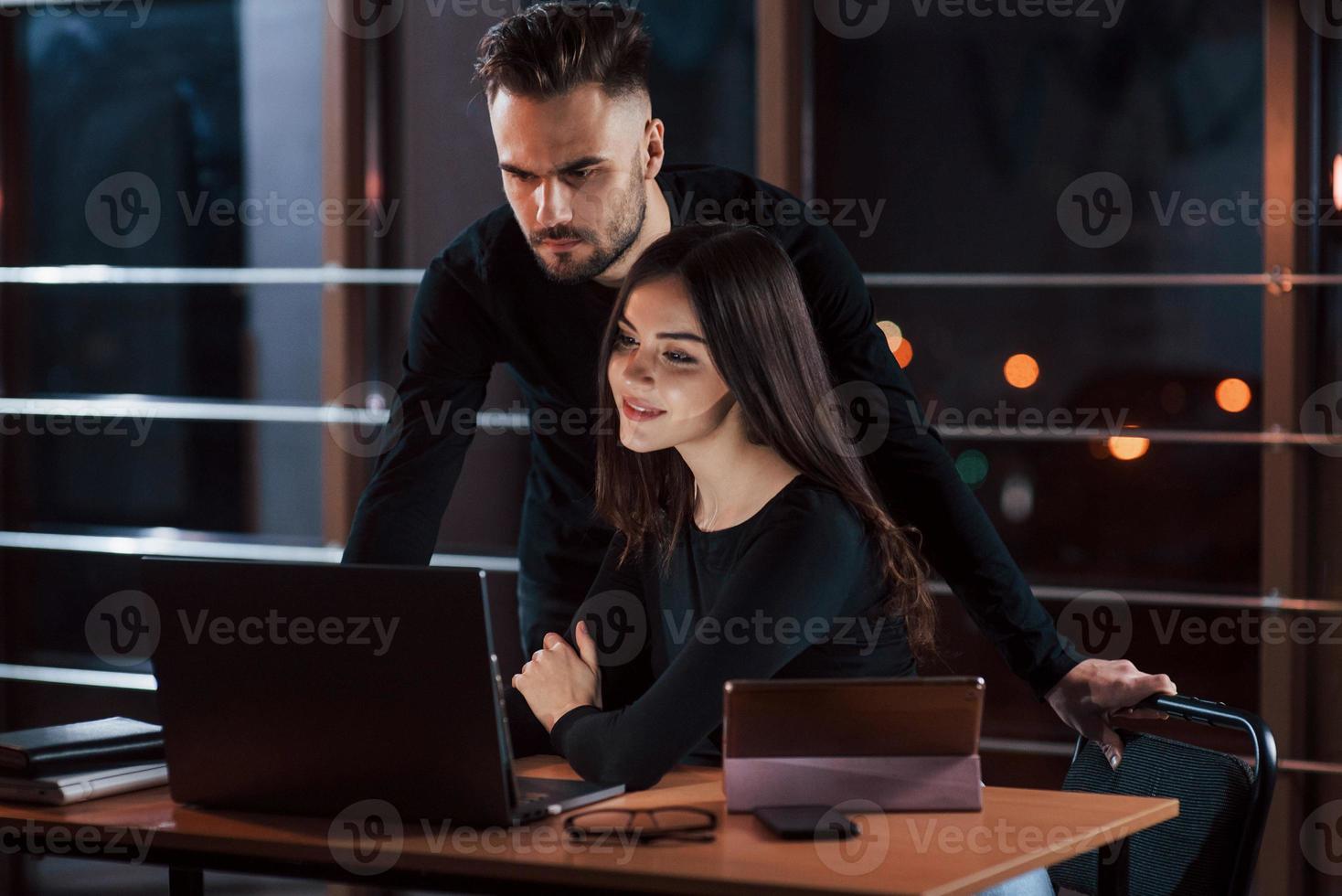 Bearded modern looking guy. Team of young business people works on their project at night time in the office photo