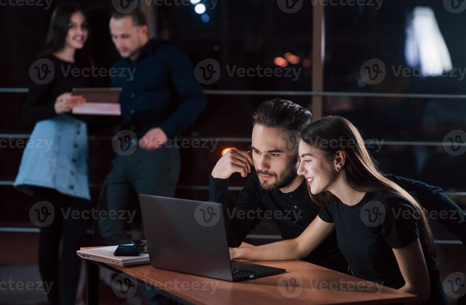 All of employees does his job. Team of young business people works on their project at night time in the office photo
