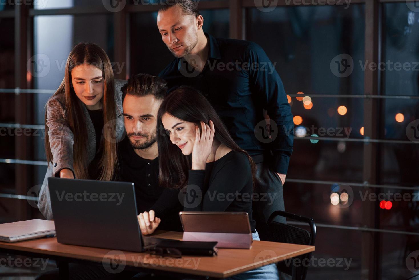 Guy teaches his employees. Team of young business people works on their project at night time in the office photo