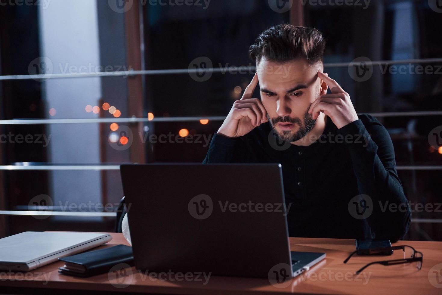 cansarse de eso. un joven hombre de negocios con estilo trabaja solo en la oficina por la noche foto