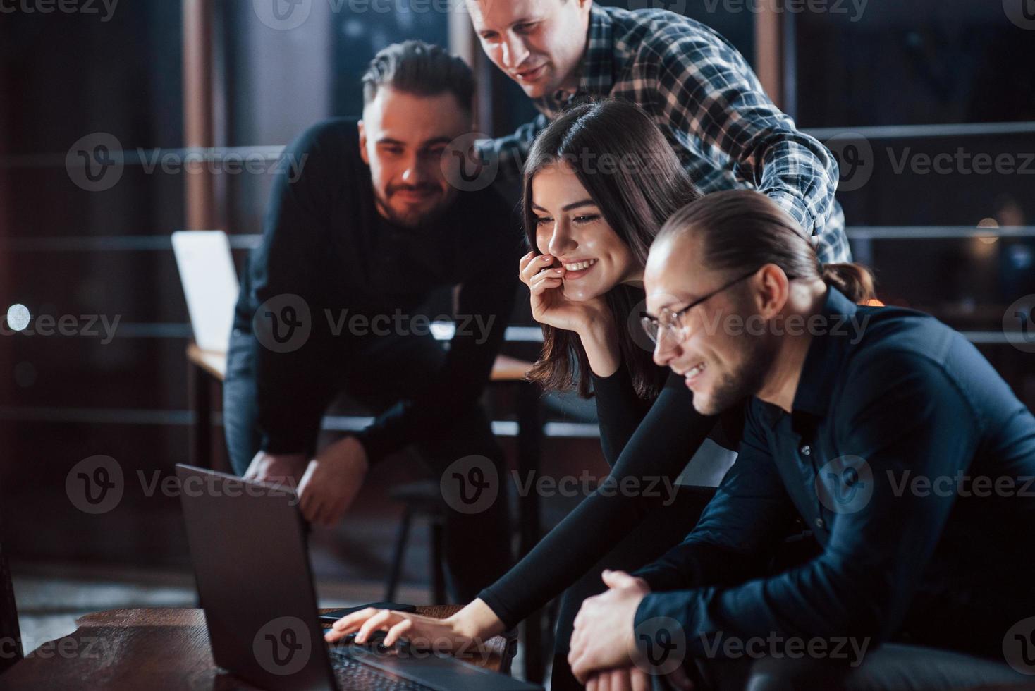 That's what happiness looks like. Team of young business people works on their project at night time in the office photo