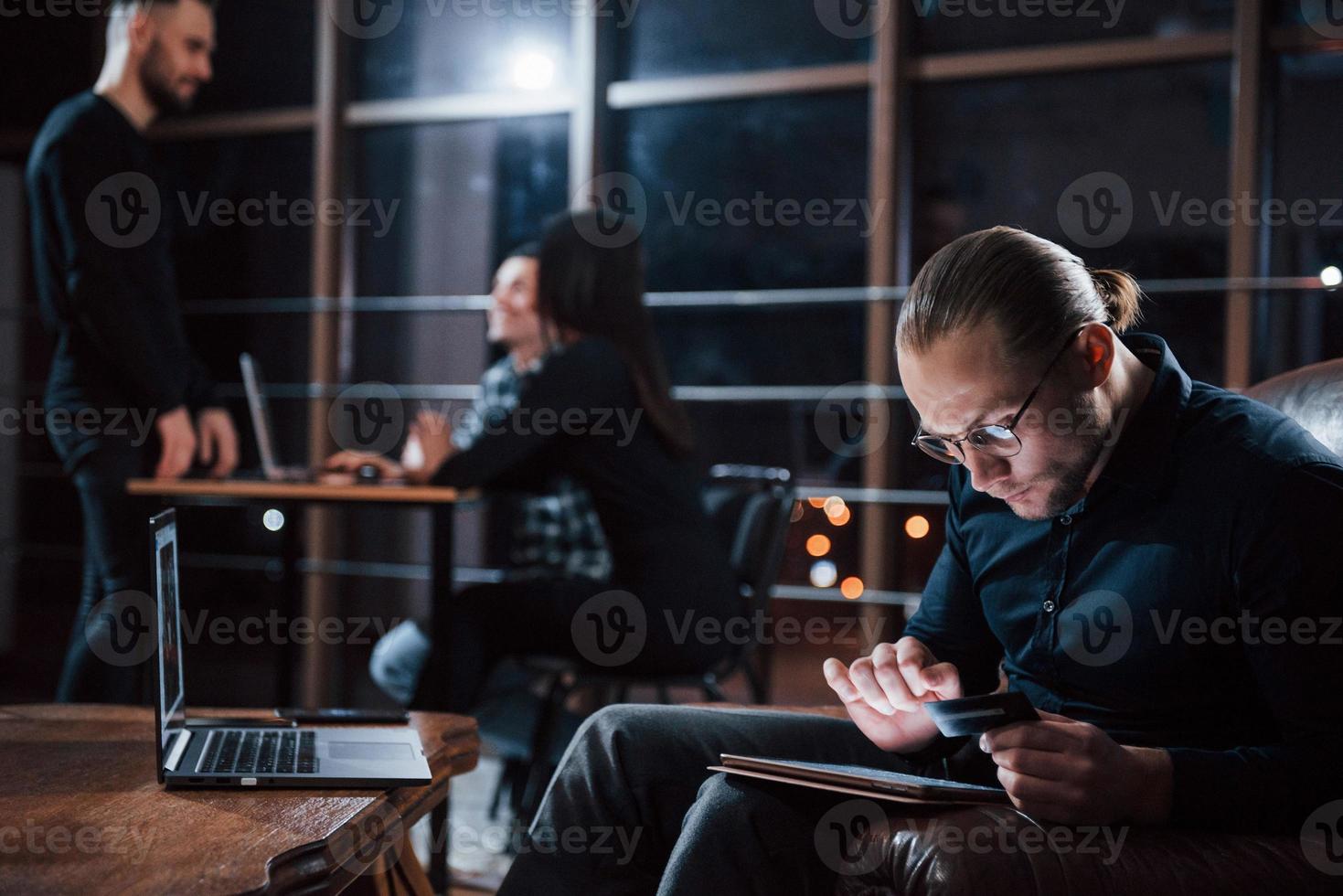 Almost done. Team of young business people works on their project at night time in the office photo