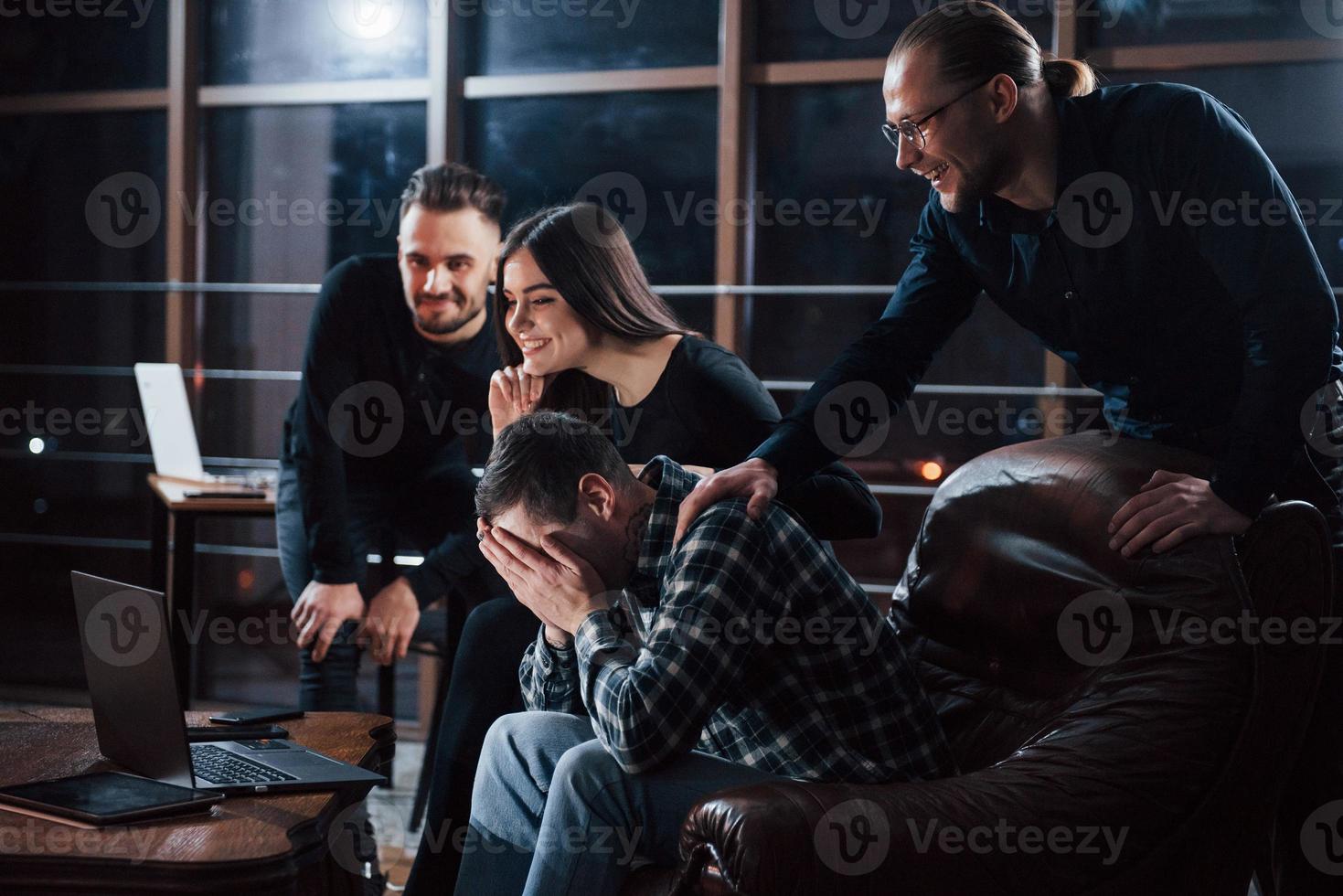 Laughing so hard. Team of young business people works on their project at night time in the office photo