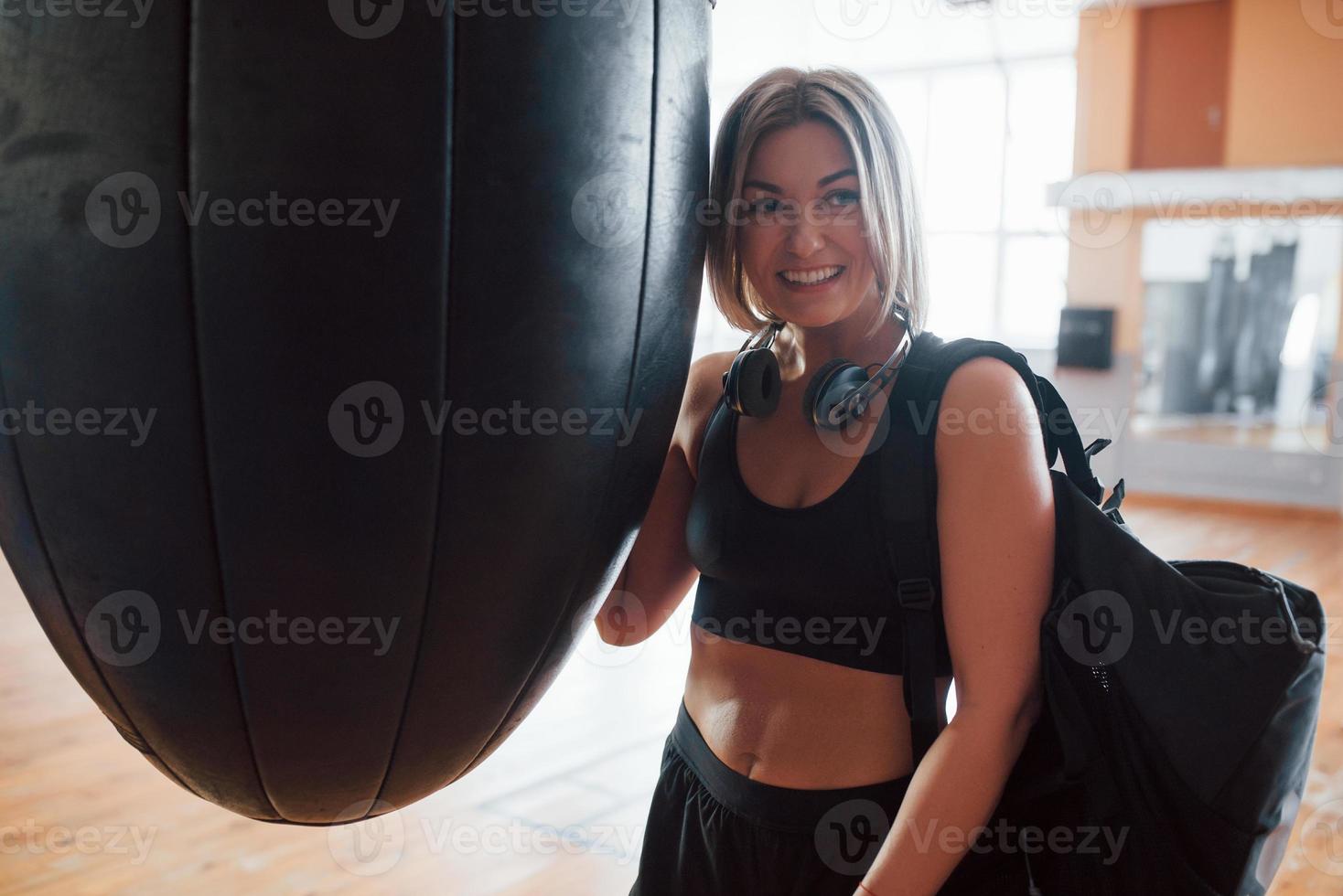 esa buena sensación después del entrenamiento. hembra adulta con bolsa negra y auriculares en el gimnasio foto