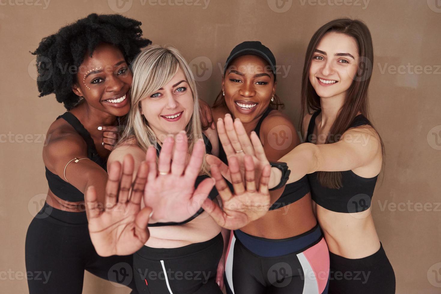 Hands in front of people. Group of multi ethnic women standing in the studio against brown background photo