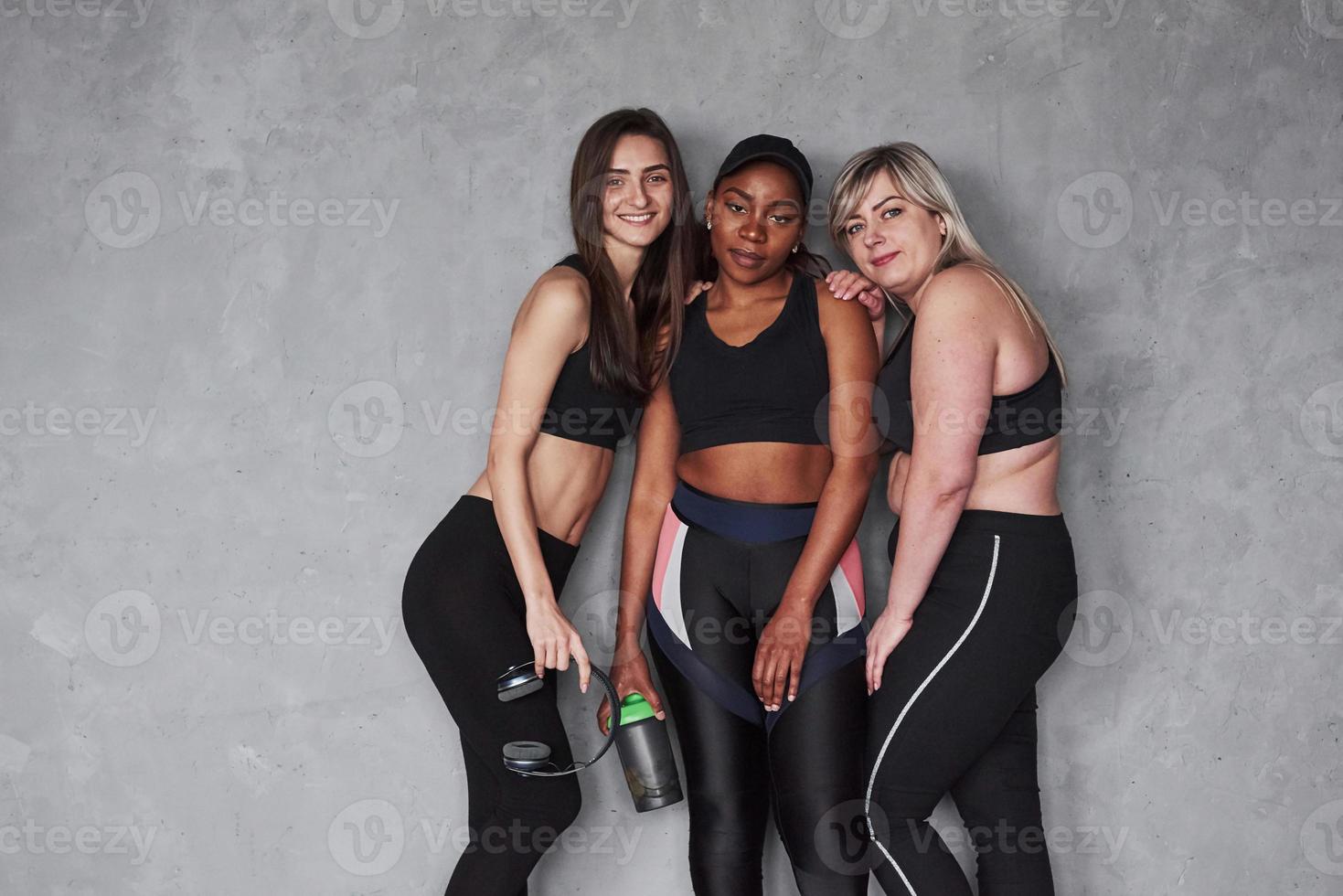 parece que la chica negra está cansada. grupo de mujeres multiétnicas de pie en el estudio con fondo gris foto