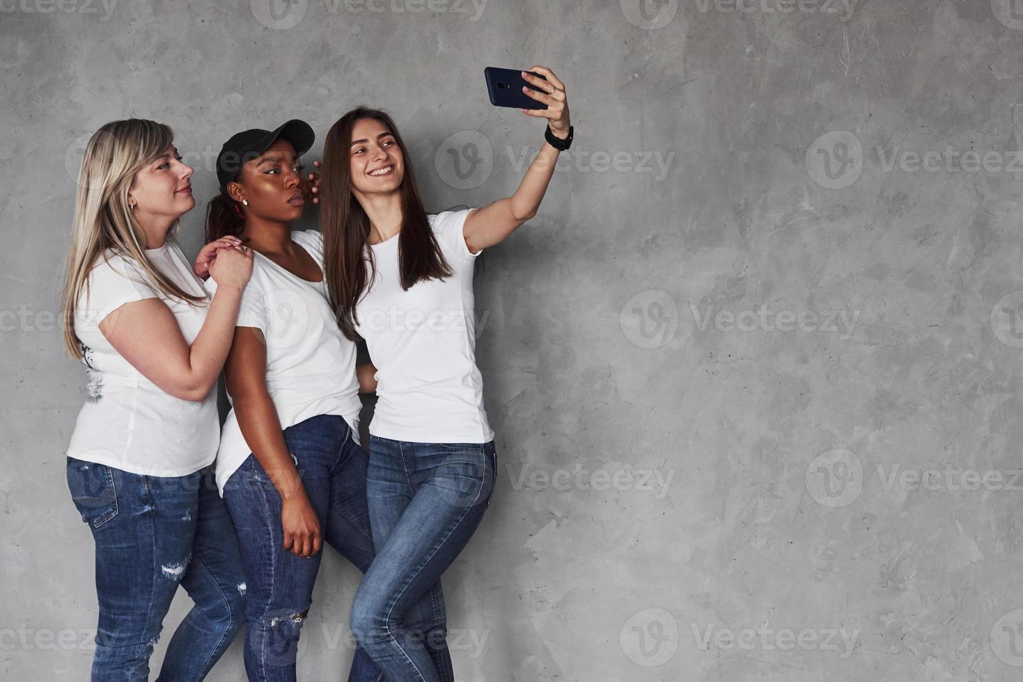 saluda a mis amigos. grupo de mujeres multiétnicas de pie en el estudio con fondo gris foto