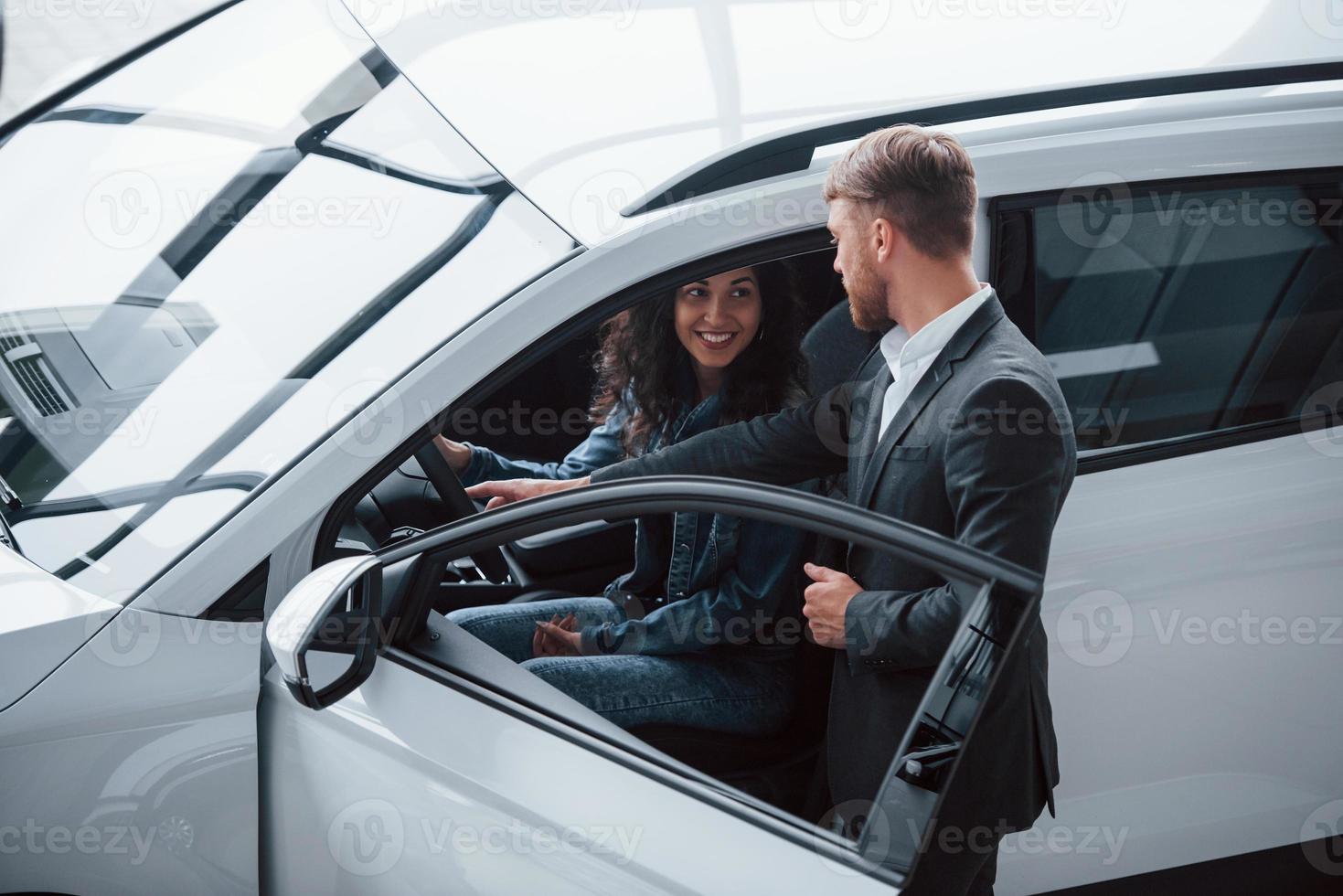 Assistance for the girl. Female customer and modern stylish bearded businessman in the automobile saloon photo