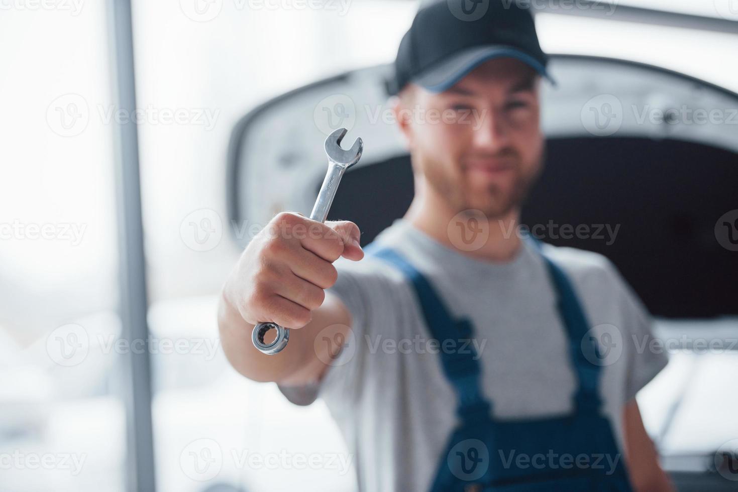 Always ready to help your vehicle. Employee in the blue colored uniform stands in the automobile salon photo