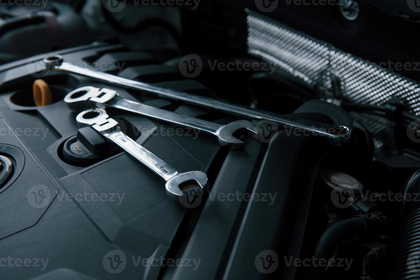Three wrenches. Repair tools lying down on the engine of automobile under the hood photo