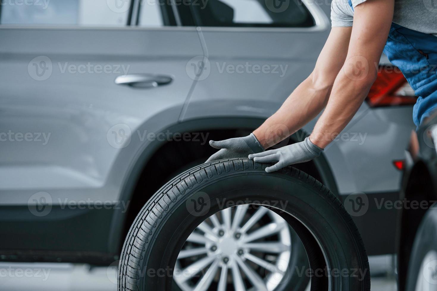 Be right back. Mechanic holding a tire at the repair garage. Replacement of winter and summer tires photo