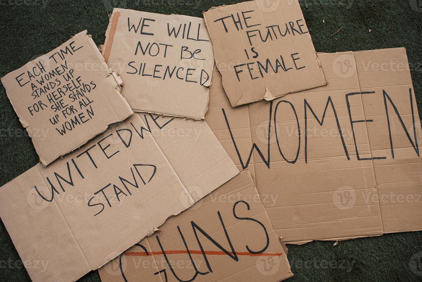 We will not be silenced. Group of banners with different feminist quotes lying on the ground photo