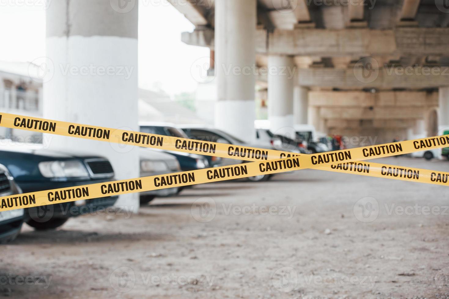 área grande cinta amarilla de precaución cerca del estacionamiento de autos durante el día. escena del crimen foto