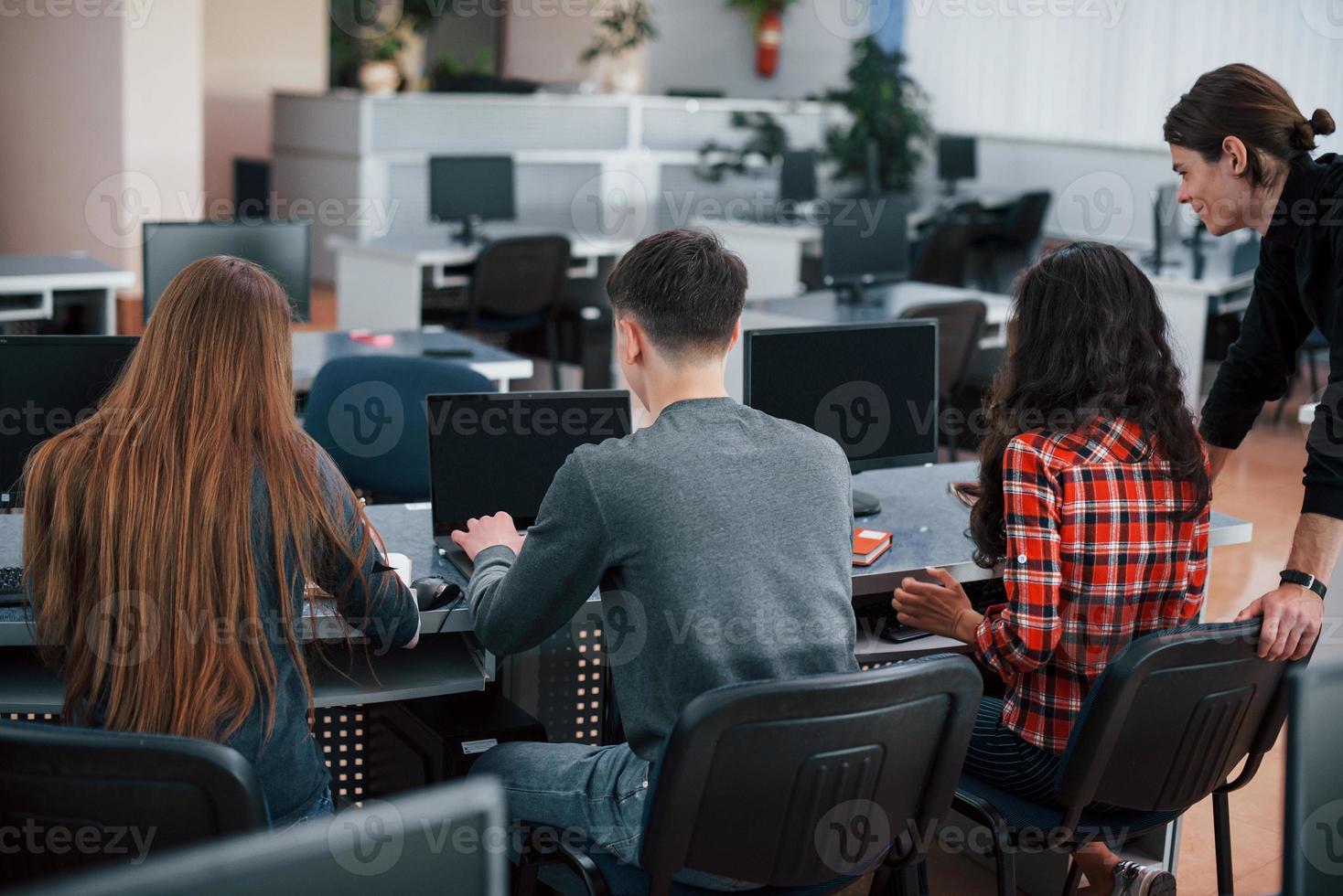 Rear view. Group of young people in casual clothes working in the modern office photo