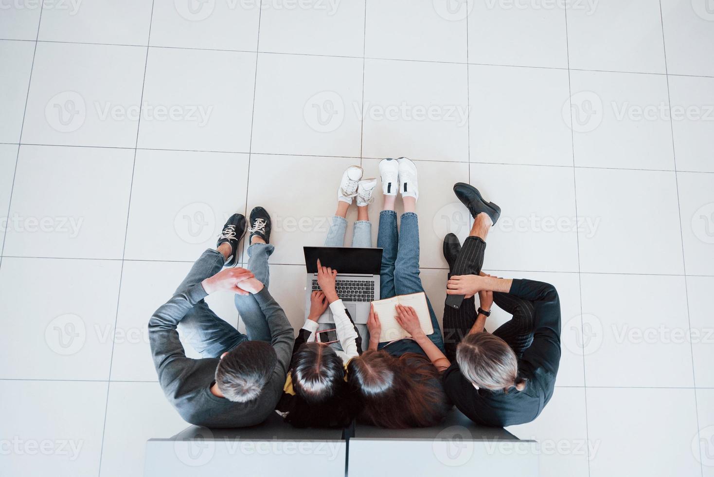 Showing something by the forefinger. Top view of young people in casual clothes working in the modern office photo