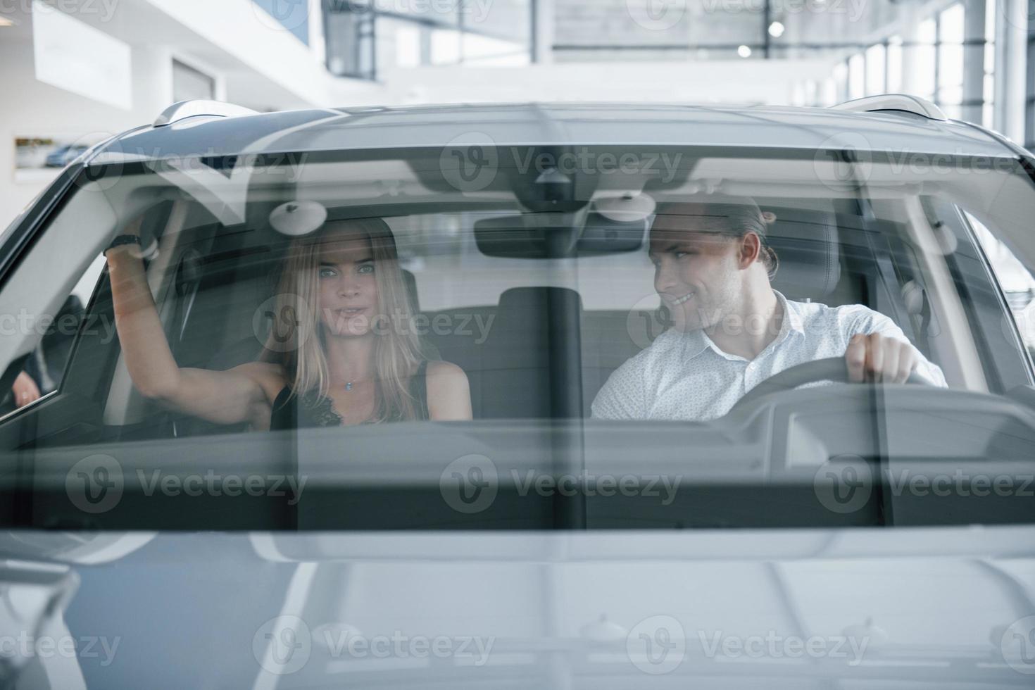 Reflection in the glass. Positive manager showing features of the new car to female customer photo