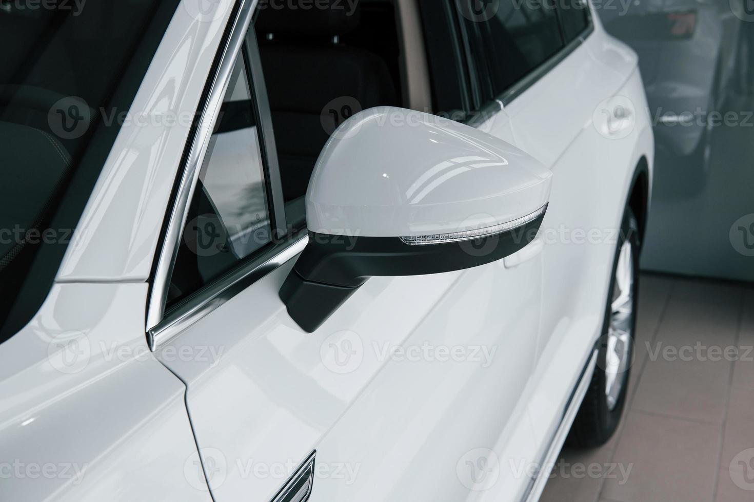 Side mirror. Particle view of modern luxury white car parked indoors at daytime photo