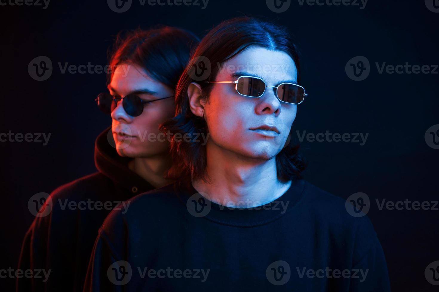 unidad de la gente. retrato de hermanos gemelos. foto de estudio en estudio oscuro con luz de neón