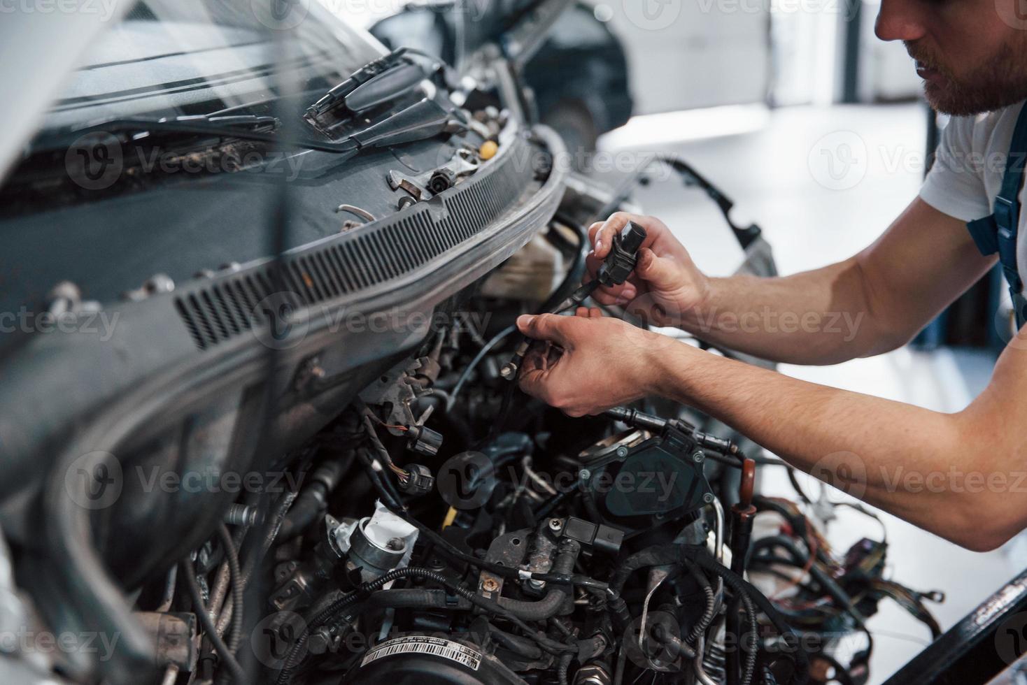 Focused photo. Employee in the blue colored uniform works in the automobile salon photo