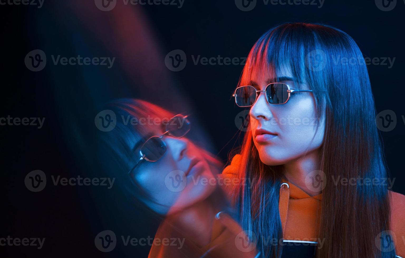 Studio shot in dark studio with neon light. Portrait of young girl photo