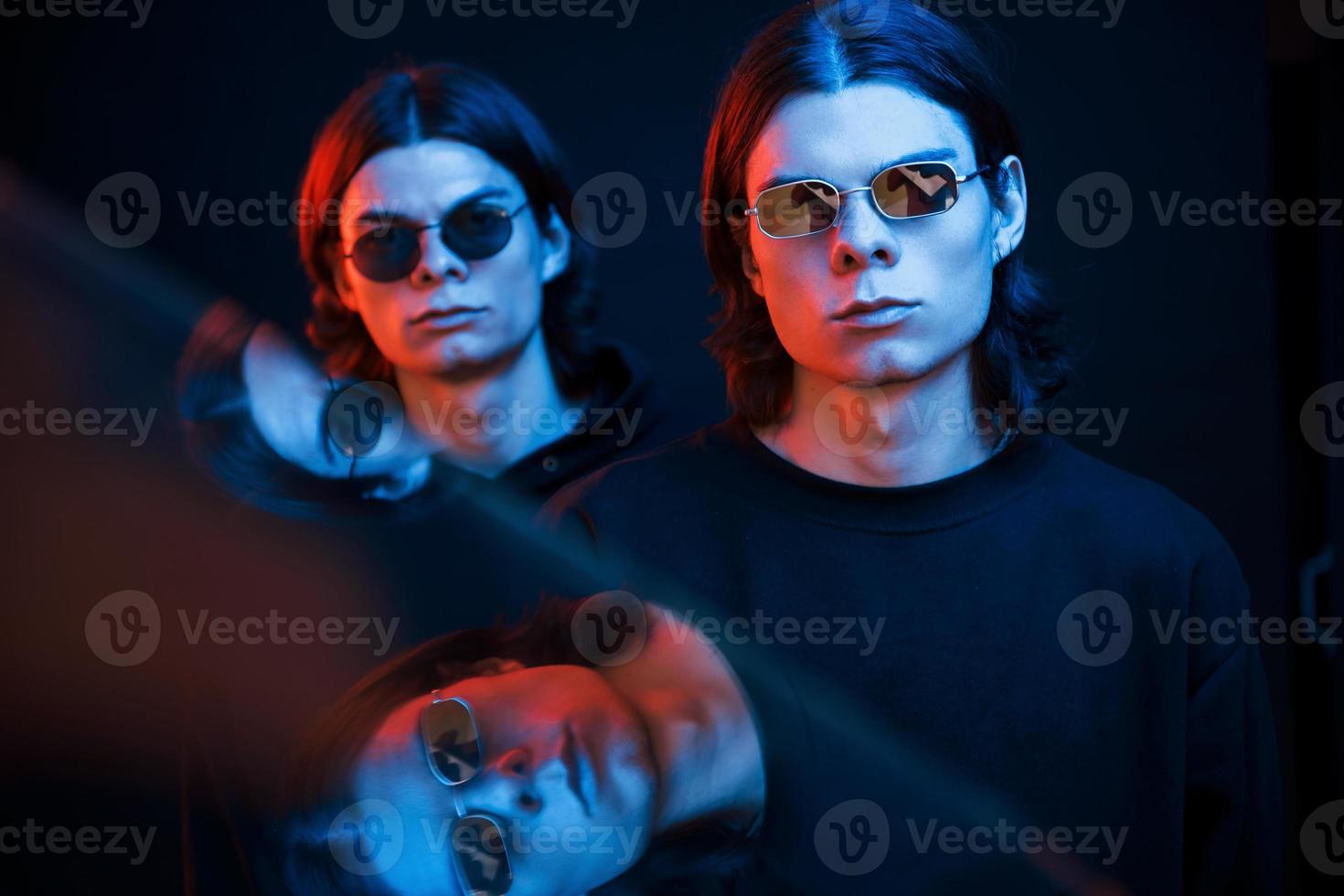 We always together. Portrait of twin brothers. Studio shot in dark studio with neon light photo